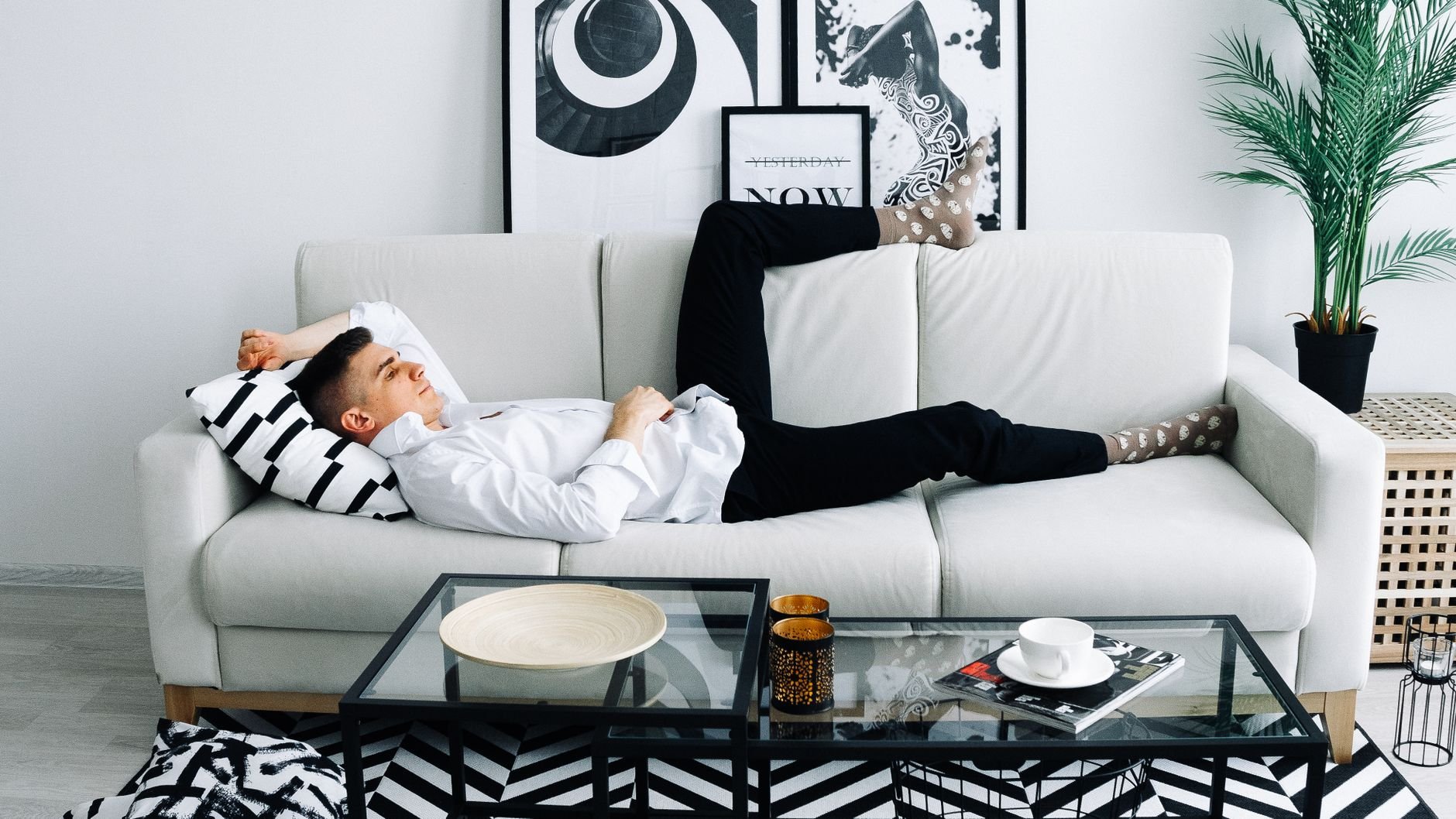 Adult man in casual wear relaxing on a white sofa in a modern living room, creating a cozy ambiance.